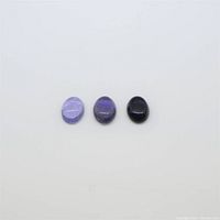 Three oval cabochon Iolite stones laid out side by side on a plain white background, showing varying purple hues.