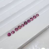 Ten round pink tourmaline gemstones displayed in a row on white background showing size and color variations.