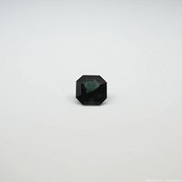 Single square cut green tourmaline gemstone shown from top view on white background.