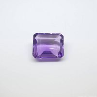 Front view of the emerald cut amethyst gemstone showing its purple color and cut facets.
