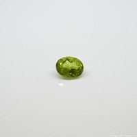Front angle of the faceted oval peridot gem, showing its cut, clarity, and yellow-green color.