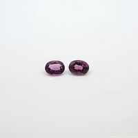 Two oval pink tourmaline gemstones shown on a white background highlighting color and clarity.