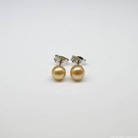 Pair of round golden pearl stud earrings set in sterling silver, front view showing size and color of pearls