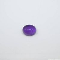 Oval purple amethyst gemstone with cabochon cut on a neutral background.