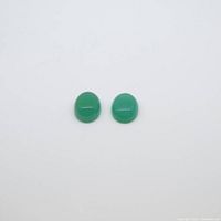 Front-facing view of the two oval green chalcedony cabochon gemstones placed side by side on a white background.