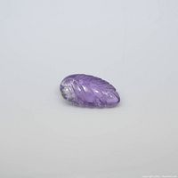 Close-up top view of the purple amethyst gemstone shaped and carved like a leaf showing the detailed veining and smooth faceted surface