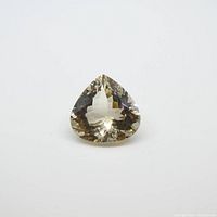 Loose pear-shaped yellow morganite gemstone laying flat on white background