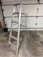 Front angle view of the 6 foot aluminum ladder placed on a concrete floor.