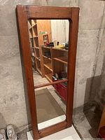 Full view of the antique pine framed full-length mirror leaning upright, showing the whole mirror and frame.