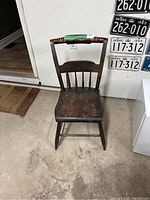 Full front view of antique wooden chair showing overall shape, curved seat, and visible wear on the finish.