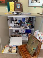 White cabinet overview showing top and interior shelves with art supplies