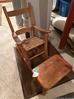 Vintage child-size wooden rocking chair with woven seat alongside a solid antique pine footstool with visible wear and surface damage.