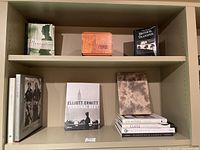 Wide view of shelf containing various coffee table books and decorative wood box.