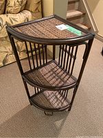 Full view of bamboo corner shelf showing all three woven rattan shelves and curved bamboo frame design.