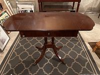 Front view of antique Duncan Phyfe drop leaf side table, extended with both leaves up, showing wood grain surface and central drawer with keyhole.