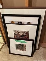 Four framed photographs of various sizes stacked together showing front views of each frame and artwork