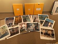 Collection of multiple 16x20 photographs laid out on floor with three yellow storage boxes behind them.