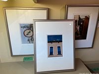 Three professionally framed photographs from France by Kelsey Mason: one of a narrow street, one architectural detail with a sign, and one of a building facade with windows.
