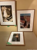 Three framed photographs: two large color French street scenes and one smaller black and white nude torso study