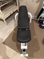 Top view of weight bench showing black padded seat and backrest with white metal frame.