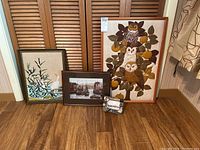 Overall view of four framed artworks against wooden shutters on floor