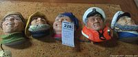 Five sailing-themed resin bosun heads displayed in a row on a flat surface.