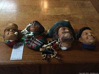 Five Bossons character heads and a small knight figurine arranged on wooden surface, showing details and size relative to auction tag.