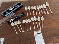 Full lot showing 19 spoons spread in rows and one boxed collector fork with medallion