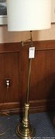 Full view of the brass floor lamp showing the white fabric shade and adjustable arm.