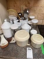 Overview of all kitchen canisters, ceramic spoon rests, and kitchen utensils in holder on countertop