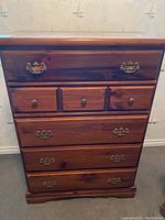 Front view of the wood highboy dresser showing drawer configuration and brass hardware.