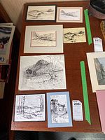 Overview photo showing six original ink and pencil sketches on a wooden table, varied sizes and subject matter of landscapes and architecture.
