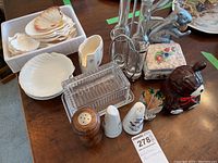 Overview of entire lot showing glass butter dish, salt and pepper shakers, squirrel nutcracker, oil and vinegar holder, honey pot, scallop serving shells, and small ceramic box.