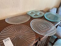 Photo of five glass serving plates placed on a wooden surface showing different textures and patterns