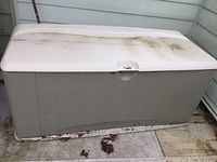 Front view of Rubbermaid plastic outdoor storage chest showing lid with dirt and discoloration.