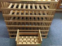 Photo showing two wooden wine storage racks side by side on carpeted floor, one large rack with horizontal slats, one smaller box-shaped rack.