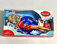 Barbie doll inside original box with Coca-Cola inflatable tube and accessories visible