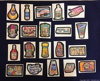 Top view of 20 Wacky Packages parody stickers laid out on black background showing various humorous brand parodies.