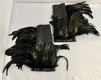 Pair of black leather glovelets with long black iridescent feathers laid flat to show the arrangement and length of feathers.