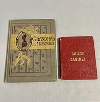 Front covers of 'Grandma's Memories' (grey cover with gold and floral details) and 'Child's Cabinet' (red embossed cover with gold lettering).