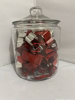Glass canister filled with metal cookie cutters, viewed from front
