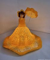 Front view of vintage MCM doll nightlight in yellow melted bead dress with matching umbrella and ruffled vanity tray.