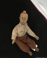 Front view of the Tintin stuffed doll sitting on black background showing facial features, shirt and pants details.