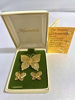 Full view of the jewelry set inside original Krementz box with brochure visible behind on white background.