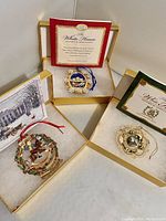 Three White House Christmas ornaments in their gold boxes with brochures visible. Ornaments from 2003, 2004, and 2005 years included.