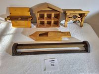 Five assorted wooden storage shelves and racks with a handcrafted wood pencil case. Items arranged on a table with white cloth.