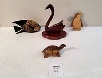 All four vintage wooden animal carvings displayed on white surface: swan, fish, penguin, turtle