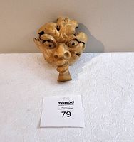 Handcrafted carved wooden face sculpture with distinct facial features and folk art style detailing.