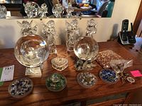 Overall lot on wooden surface showing crystal balls, angel figurines, glass dishes with beads, and small trinkets.