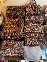 Six leopard print cosmetic cases and one gray mesh pouch arranged on table